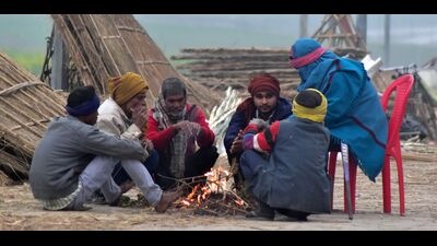 People huddle around a bonfire to keep warm and beat the chill on yet another foggy and cloudy day in Prayagraj on Thursday. (HT PHOTO)