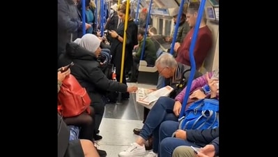 The image shows a stranger helping an elderly person read a newspaper during their commute. (rosiemegangill)