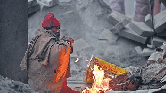 A man huddled around a bonfire during morning hours amid cold weather at IP Extension, in Delhi on Thursday. (Sanjeev Verma/HT Photo)