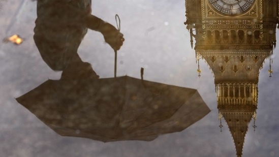 Britain Census: A woman with an umbrella and the Elizabeth Tower also known as Big Ben are reflected in a puddle in London. (AP)