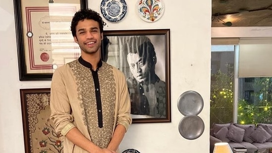 Actor Babil Khan stands next to a photograph of his father, late actor Irrfan Khan. 