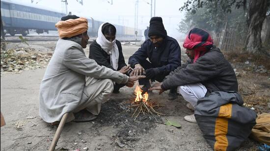People around a bonfire at Daulatabad village near Laxman Vihar in Gurugram on Thursday morning. (Parveen Kumar/HT Photo)
