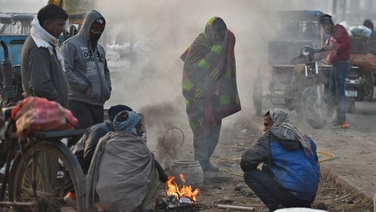People warm themselves around a bonfire on a cold winter morning at Ghazipur market in New Delhi. (Raj K Raj/HT Photo)