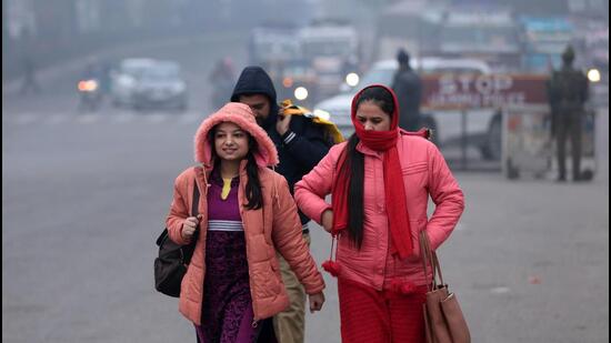 People clad in woollens in Jammu on Sunday. (PTI)