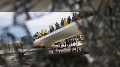 Supporters of Brazil's former President Jair Bolsonaro are pictured through broken glass as they hold a demonstration against President Luiz Inacio Lula da Silva, in Brasilia, Brazil. (REUTERS)