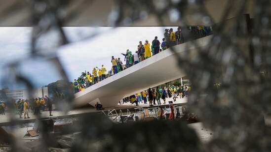 Supporters of Brazil's former President Jair Bolsonaro are pictured through broken glass as they hold a demonstration against President Luiz Inacio Lula da Silva, in Brasilia, Brazil.(REUTERS)