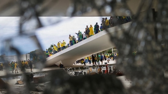 Supporters of Brazil's former President Jair Bolsonaro are pictured through broken glass as they hold a demonstration against President Luiz Inacio Lula da Silva, in Brasilia, Brazil.(REUTERS)