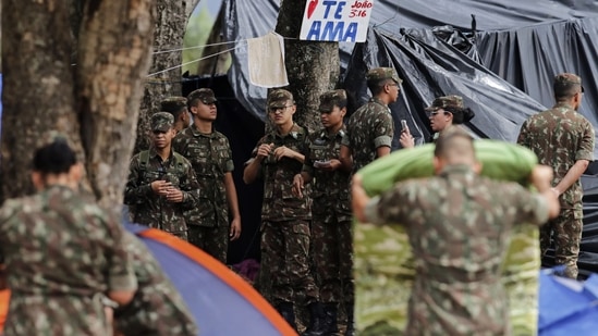 Soldiers clear out an encampment set up by supporters of former Brazilian President Jair Bolsonaro outside army headquarters, where a sign reads in Spanish "Jesus loves you" in Brasilia, Brazil.(AP)