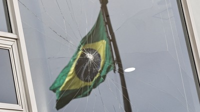 Brazil's flag is reflected on a broken window at Planalto Palace, on January 9. Lula, who took office on January 1 after a bitterly divisive election win over Bolsonaro, returned to work in the pillaged presidential palace where protestors had trashed artwork and offices, shattered windows and doors, and dragged furniture into a reflecting pool. (Ueslei Marcelino / Reuters) Brazil's flag is reflected on a broken window at Planalto Palace, on January 9. Lula, who took office on January 1 after a bitterly divisive election win over Bolsonaro, returned to work in the pillaged presidential palace where protestors had trashed artwork and offices, shattered windows and doors, and dragged furniture into a reflecting pool. (Ueslei Marcelino / Reuters)