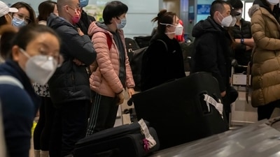 China reopening: Travelers wearing face masks wait for their luggage in the international arrivals. (AP) China reopening: Travelers wearing face masks wait for their luggage in the international arrivals. (AP)