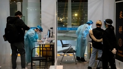 Covid In China: Workers wearing protective suits stand in a booths to take Covid-19 tests. (AP) Covid In China: Workers wearing protective suits stand in a booths to take Covid-19 tests. (AP)