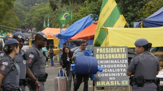 Bolsonaro supporters leave their encampment outside army headquarters as military police stand watch in Sao Paulo, on January 9. Brazilian security forces arrested 1,500 people and cleared protest camps that had been used as a base for the sea of protesters who ran riot inside government buildings on January 8. (Andre Penner / AP)