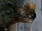 An aerial view of a vehicle stuck in a sinkhole in the Chatsworth section of Los Angeles, on January 10. Sinkholes swallowed cars and raging torrents swamped towns and swept away a small boy on Tuesday as California was hit by a powerful string of Pacific storms.  (Jae C. Hong / AP )