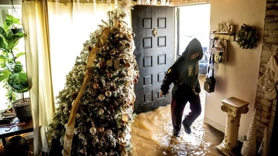 Brenda Ortega, 15, walks through water in her flooded home in Merced, California on January 10. The National Weather Service has warned of a “relentless parade of atmospheric rivers” as reported by AP. (Noah Berger / AP Photo)