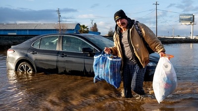 A resident carries his belongings amid flooded waters in Merced, California, on January 10. California's Governor Gavin Newsom declared a state of emergency and was granted, a presidential emergency declaration. (Noah Berger / AP)