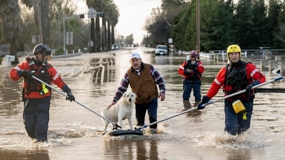 San Diego firefighters help Humberto Maciel rescue his dog from his flooded home in Merced, California, on January 10. Evacuation orders were issued in Santa Cruz County for about 32,000 residents living near rain-swollen rivers and creeks, said Melodye Serino, the deputy county administrative officer, as reported by AP. (Josh Edelson / AFP)