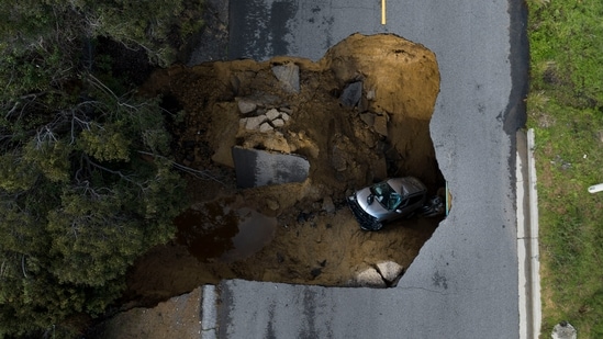 An aerial view of a vehicle stuck in a sinkhole in the Chatsworth section of Los Angeles, on January 10. Sinkholes swallowed cars and raging torrents swamped towns and swept away a small boy on Tuesday as California was hit by a powerful string of Pacific storms.  (Jae C. Hong / AP )