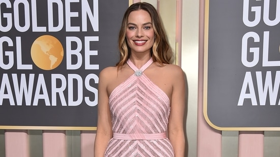 Margot Robbie makes a statement in a light pink gown featuring a halter neckline, intricate embroidery and a figure-skimming silhouette. A stylish brooch, open wavy locks, pink-hued makeup, and high heels rounded off her awards-show look.&nbsp;(Invision)