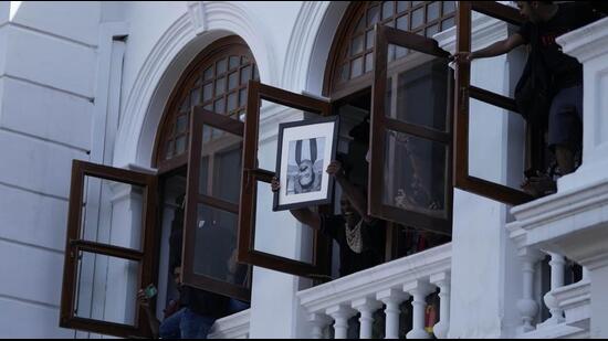 A protester holds a portrait of former Sri Lankan Prime Minister Mahinda Rajapaksa upside down after storming the office of Prime Minister Ranil Wickremesinghe, demanding he resign after Rajapaksa fled the country amid economic crisis in Colombo, Sri Lanka, on July 13, 2022. (AP)