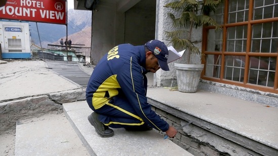 An SDRF official taking measurements of the crack that appeared on the wall during recent land subsidence at Joshimath, in Chamoli on Wednesday. (ANI)