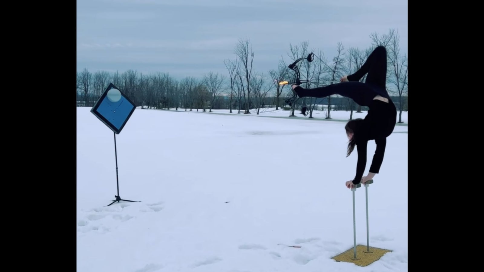 Woman shoots balloon with flaming arrow while doing a handstand in viral video. Watch