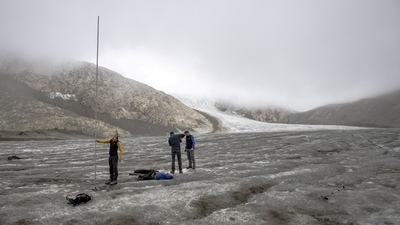 In this file photo from September 2, 2022, members of the Glacier Monitoring in Switzerland (GLAMOS) are seen holding a 6.5-meter-long metal bar that was completely covered by ice in September 2021. They found it lying on the ground in 2022 after the record melting of ice due to the summer heatwave on the Gries Glacier, in Gries, Switzerland. (Denis Balibouse / Reuters) In this file photo from September 2, 2022, members of the Glacier Monitoring in Switzerland (GLAMOS) are seen holding a 6.5-meter-long metal bar that was completely covered by ice in September 2021. They found it lying on the ground in 2022 after the record melting of ice due to the summer heatwave on the Gries Glacier, in Gries, Switzerland. (Denis Balibouse / Reuters)
