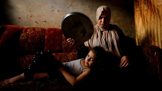 A Palestinian woman fans her daughter with a tray amid a heatwave and lengthy power cuts in Gaza City, on August 1, 2022. "2022 was yet another year of climate extremes across Europe and globally," deputy head of the Copernicus climate change service Samantha Burges said, AFP reported. (Mohammed Salem / Reuters)