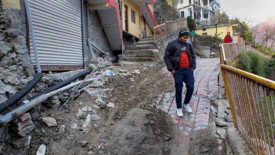 A man walks near damaged buildings in Joshimath. (PTI)