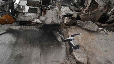 Artwork by Banksy seen over the ruins in Borodyanka, Ukraine, on January 12, amid the Russian invasion of Ukraine. The British artist is selling 50 new limited edition screen-prints through the Legacy of War Foundation to raise funds to support Ukrainian civilians affected by conflict. (Sergei Supinsky / AFP) Artwork by Banksy seen over the ruins in Borodyanka, Ukraine, on January 12, amid the Russian invasion of Ukraine. The British artist is selling 50 new limited edition screen-prints through the Legacy of War Foundation to raise funds to support Ukrainian civilians affected by conflict. (Sergei Supinsky / AFP)