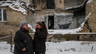 Local residents affected by the ongoing conflict seen near artwork by world-renowned graffiti artist Banksy at the wall of a destroyed building in Horenka, on November 19, 2022. The artist confirmed he was behind seven murals that appeared on destroyed buildings around Kyiv. (Gleb Garanich / REUTERS) Local residents affected by the ongoing conflict seen near artwork by world-renowned graffiti artist Banksy at the wall of a destroyed building in Horenka, on November 19, 2022. The artist confirmed he was behind seven murals that appeared on destroyed buildings around Kyiv. (Gleb Garanich / REUTERS)