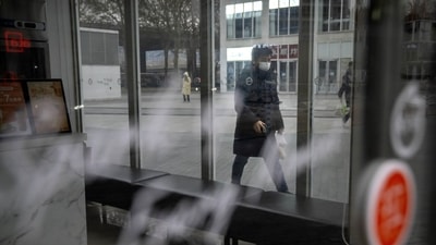 Covid In China: A commuter wearing a face mask walks past a closed shop in the central business district in Beijing. (AP) Covid In China: A commuter wearing a face mask walks past a closed shop in the central business district in Beijing. (AP)
