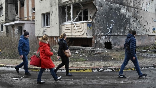 People walk past a Banksy’s graffiti on a wall of a heavily damaged residential building in Irpin, northwest of Kyiv, on December 23, 2022, According to AFP, to get one of the £5,000 ($6,080) prints, Banksy supporters have to register online with the charity. However, a message posted this week on the website said it had “received over 1 million requests (and 3,500 hostile attacks from Russian IP addresses).”(Genya Savilov / AFP)