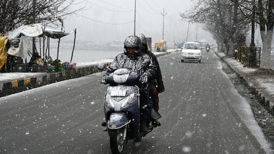 Commuters pass by Dal Lake. The inclement weather resulted in the closure of the Srinagar-Jammu national highway - the only all-weather road connecting the Valley with the rest of the country.(Waseem Andrabi/HT photo)