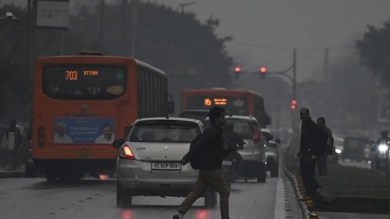 A person crossing the road at Connaught Place as it rains on Thursday evening. (Raj K Raj/HT Photo)