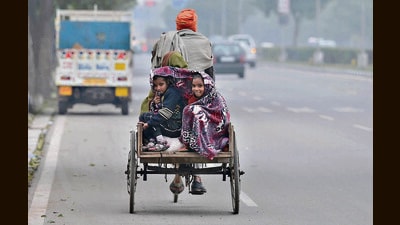 Children bundled in a blanket while riding their father’s cart in Chandigarh on a chilly Saturday morning. (Ravi Kumar/HT)
