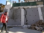 A passerby looks at the rubble of a wall that got damaged due to continuous land subsidence, in Joshimath on Sunday. (ANI) A passerby looks at the rubble of a wall that got damaged due to continuous land subsidence, in Joshimath on Sunday. (ANI)