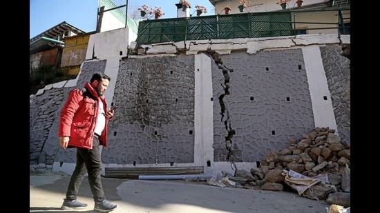 A passerby looks at the rubble of a wall that got damaged due to continuous land subsidence, in Joshimath on Sunday. (ANI)
