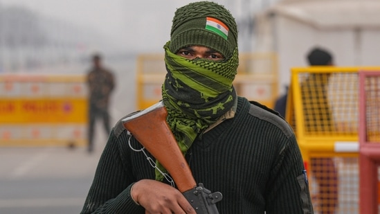 Security personnel stand guard at Kartavya Path as a contingent rehearses for the Republic Day Parade 2023 during a cold and foggy morning in New Delhi. (PTI)