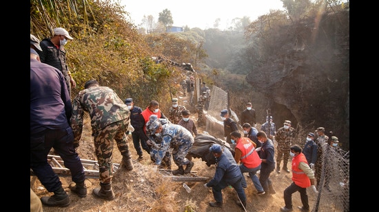Rescue workers recovering the body of a victim of a passenger plane that crashed in Pokhara, Nepal on Sunday. (AP)