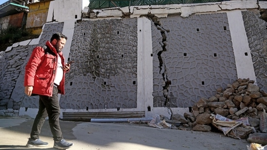 A passerby looks at the rubble of a wall that got damaged due to continuous land subsidence, in Joshimath on Sunday. (ANI)