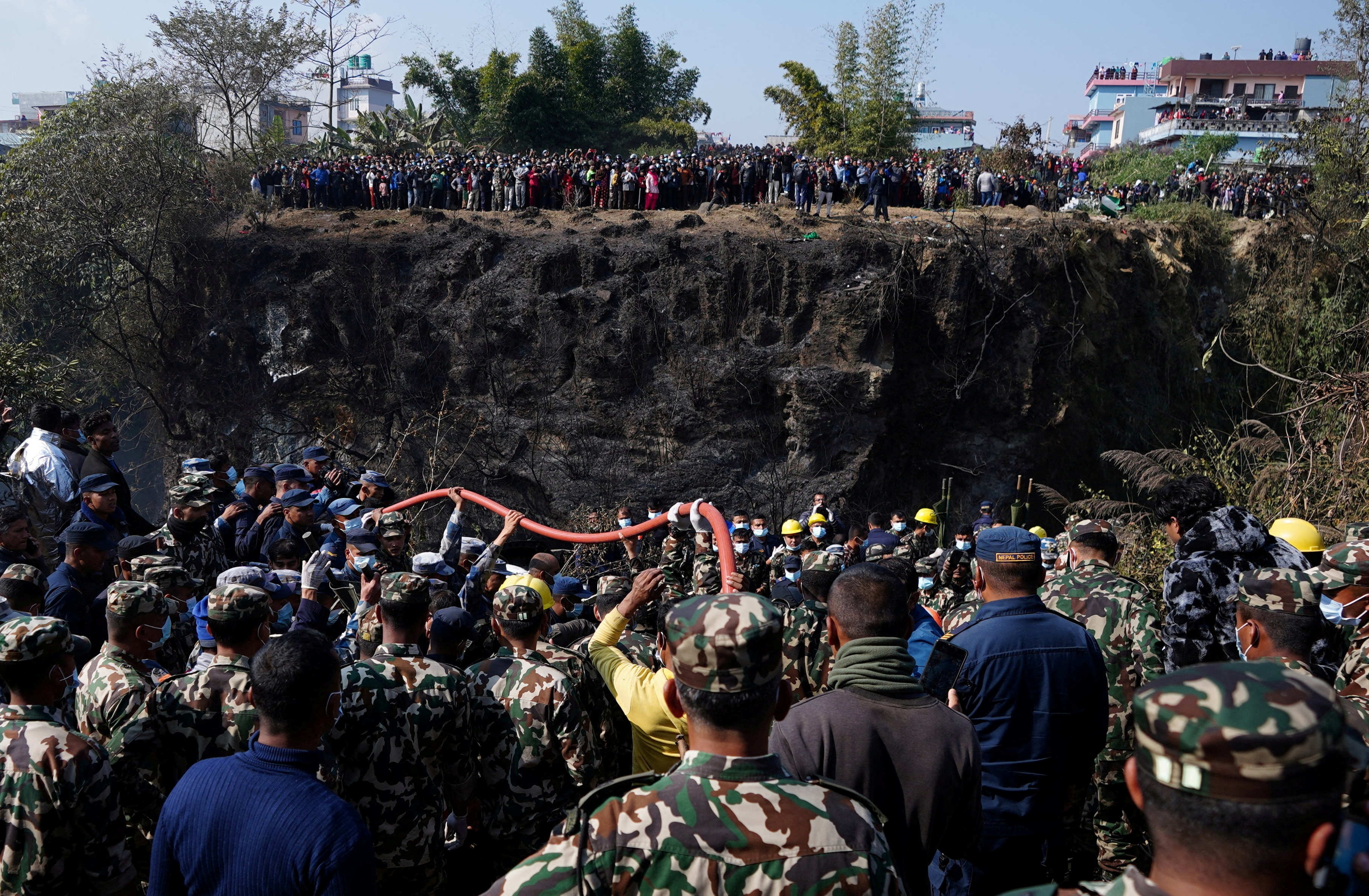 Crowds gather as rescue teams work to retrieve bodies at the crash site of an aircraft carrying 72 people in Pokhara. (Reuters)