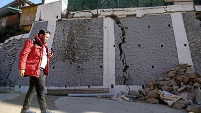 A passerby looks at the rubble of a wall that got damaged due to continuous land subsidence, in Joshimath on Sunday. (ANI) A passerby looks at the rubble of a wall that got damaged due to continuous land subsidence, in Joshimath on Sunday. (ANI)