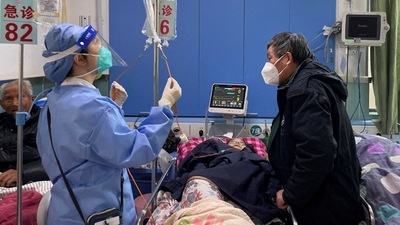 A medical worker checks the IV drip treatment of a patient lying on a bed in the emergency department of a hospital amid the coronavirus disease outbreak in Shanghai. (REUTERS)