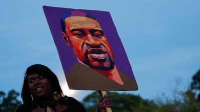 A woman holds a placard depicting George Floyd during a demonstration on the first anniversary of his death, in Brooklyn, New York City, New York, US. (REUTERS)