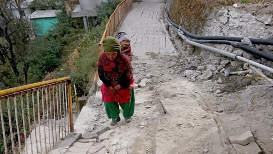 A local resident passing through a damaged path due to land subsidence at Joshimath, in Chamoli on Tuesday. (ANI)