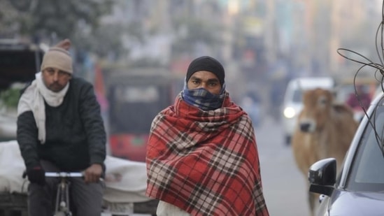 People on a cold winter morning at Khandsa road in Gurugram on Monday, (Parveen Kumar/HT photo)