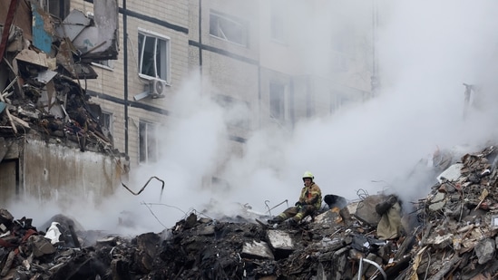 Russia-Ukraine War: An emergency personnel looks on at the site where an apartment block was heavily damaged by a Russian missile strike, amid Russia's attack on Ukraine, in Dnipro.(Reuters)