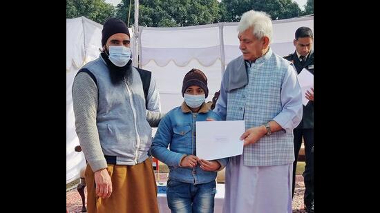 Jammu and Kashmir lieutenant governor Manoj Sinha hands over a cheque to a family member of a deceased National Health Mission (NHM) employee, who lost his life while serving during Covid, in Jammu on Wednesday. (ANI)