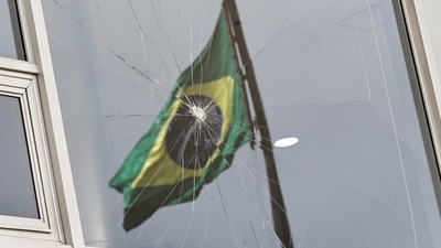Brazil Riots: Brazil's flag is reflected on a broken window at Planalto Palace. (Reuters)