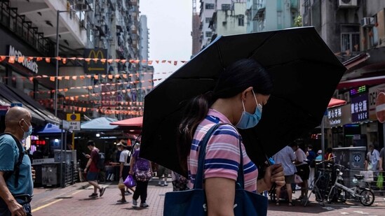 Covid In Hong Kong: A woman uses an umbrella to shield herself from the sun in Hong Kong.(AFP)